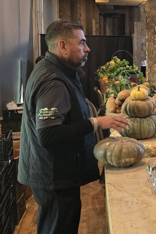 Don Espinoza, con la chamarra de Espinoza's Produce, acomodando calabazas en la mesa